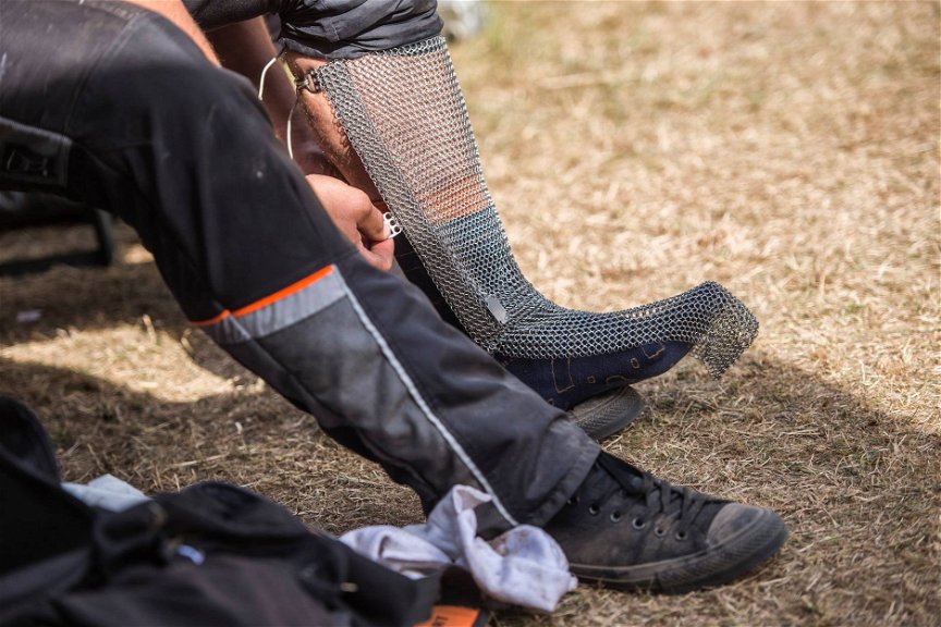 STIHL TImbersports Athlet legt einen Schienbein- und Fußschutz aus einem Kettengewebe an.