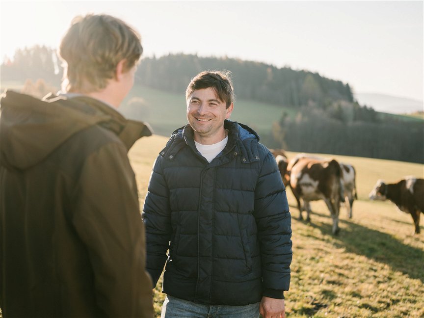 Zwei Bauern sprechen miteinander auf einer Kuhweide