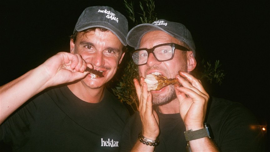 zwei Männer die Grillhendl essen